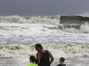 Laura Cunningham, 10,left, Hunter Shows, centre, and Brandon Perry, 10, right, watch the waves crash from Tropical Storm Gordon on Tuesday, Sept. 4, 2018 in Dauphin Island, Ala.