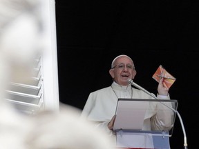 Pope Francis shows a crucifix during the Angelus noon prayer he delivers from the window of his studio overlooking St. Peter's Square at the Vatican, Sunday, Sept. 16, 2018. Tens of thousands of faithful have been treated to gifts from the pontiff, tiny crucifixes, distributed by nuns, refugees and some of Rome's homeless and poor after the pope's traditional Sunday appearance to pilgrims and tourists in the square.