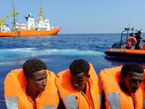 Migrants on a wooden boat are seen after receiving life jackets from crew members of the rescue boat Aquarius (background) on August 10, 2018 in the international waters off the Lybian coast.