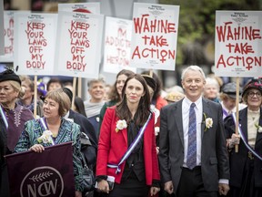 New Zealand Prime Minister Jacinda Ardern, center, and the Mayor of Auckland, Phil Goff attend the Suffrage 125 year sunrise celebration in Auckland, New Zealand, Wednesday, Sept. 19. 2018. New Zealand became the first nation in the world to allow women to vote 125 years ago, and hundreds of people celebrated the anniversary by turning out to gatherings and speeches with some wearing period costumes or the white camellia flowers -- a symbol of the movement.