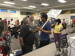 In this Thursday, Sept. 6, 2018, photo, protesters talk at a community meeting held in the South Phoenix neighborhood to provide information about plans for a 5.5-mile extension of the light rail into the community, in Phoenix. The plan progressed quietly until some shop owners in the mostly Hispanic and black neighborhoods complained that reducing car traffic from four to two lanes on the affected thoroughfare could hurt business.