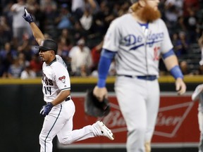 Arizona Diamondbacks' Eduardo Escobar (14) rounds the bases after hitting a walk-off home run as Los Angeles Dodgers third baseman Justin Turner leaves the field during the ninth inning of a baseball game, Tuesday, Sept. 25, 2018, in Phoenix. The Diamondbacks won 4-3.