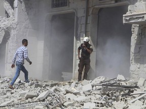 This photo provided by the Syrian Civil Defense group known as the White Helmets, shows a civil defense worker speaking on his radio next to a building that was attacked by a Syrian government airstrike, in Hobeit village, near Idlib, Syria, Sunday, Sept. 9, 2018. The White Helmets and a conflict monitoring group said Sunday that government and Russian forces have resumed their bombing of the opposition's last stretch of territory in the country, killing an infant girl and damaging a hospital. (Syrian Civil Defense White Helmets via AP)