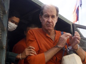 FILE - In this Aug. 29, 2018, file photo, Australian filmmaker James Ricketson, right, is helped off a prisoner truck upon his arrival at Phnom Penh Municipal Court in Phnom Penh, Cambodia. Cambodia has pardoned Ricketson Friday, Sept. 21, 2018, after being sentenced last month to six years in jail on an espionage charge in a trial that was widely criticized as unfair