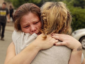 FILE - In this July 28, 2018, file photo, Carla Bledsoe, facing camera, hugs her sister Sherry outside of the sheriff's office after hearing news that Sherry's children James, 4, and Emily 5, and grandmother were killed in a wildfire in Redding, Calif. While California officials quickly determined an arsonist started the wildfire burning southeast of Los Angeles and that sparks from a vehicle produced the deadly wildfire in the city of Redding, causes for many of the state's worst blazes in the past decade remain a mystery.