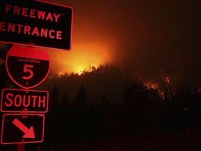 In this Friday, Sept. 7, 2018 photo, wildfires continued to burn on the ridge line east of I-5 just south of Gibson Rd., exit near Shasta-Trinity National Forest, Calif. A roaring wildfire that has shut down a stretch of a major interstate in a rural area near the California-Oregon border has nearly doubled in size. The blaze in California's Shasta-Trinity National Forest is burning out of control and crews Saturday, Sept. 8, are scrambling to prevent it from reaching mountain communities to the north.