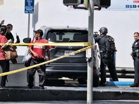 An Los Angeles police offer directs Jack in the Box employees from the restaurant after a shooting in the Van Nuys section of Los Angeles on Thursday, Sept. 20, 2018. Los Angeles police say a shooting near a charter high school wounded a male teenage student and a female school employee. Sgt. Barry Montgomery says he cannot immediately say whether the victims were targeted in the shooting Thursday at a Jack in the Box restaurant across the street from the school. A Fire Department spokesperson said both victims have extremity wounds and were transported to a hospital in stable condition.