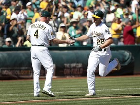 Oakland Athletics' Matt Olson (28) is congratulated by third base coach Matt Williams (4) as he rounds the base after hitting a solo run home run against the Minnesota Twins during the second inning in a baseball game in Oakland, Calif., Sunday, Sept. 23, 2018.