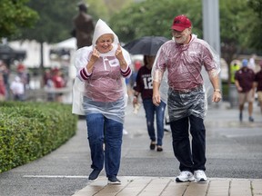 Arkansas fans Mary Ann and Ed Piker, of Fairfield Bay, Arkansas, walk into AT&T Stadium as a light rain falls before an NCAA college football game against Texas A&M, Saturday, Sept. 29, 2018, in Arlington, Texas.