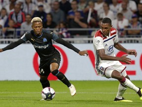 Marseille's Mua Njie Clinton, left, challenges for the ball with Lyon's Marcelo Guedes Filho, right, during their French League One soccer match in Decines, near Lyon, central France, Sunday, Sept. 23, 2018.