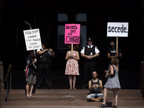 Protesters stand in the archway entrance to Queen's Park during a protest prior to the legislative house sitting on Saturday, Sept. 15, 2018.