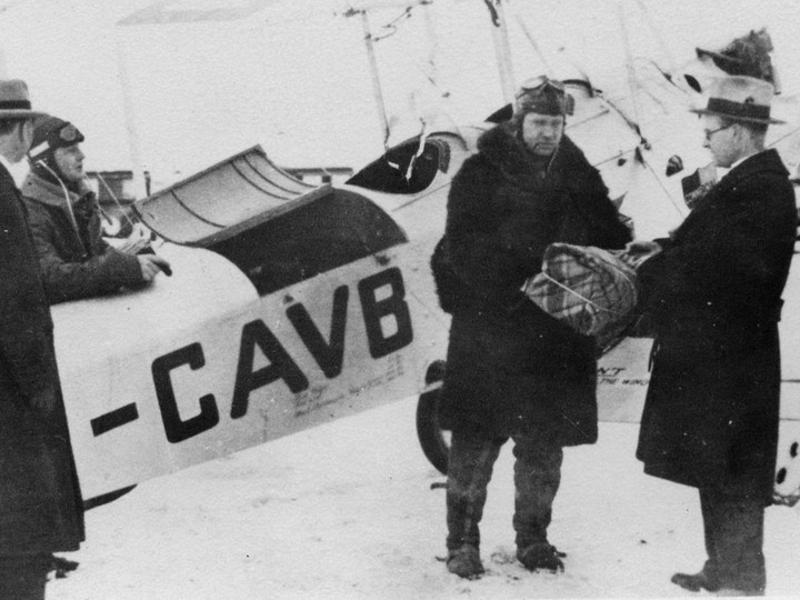  Bush pilot Wilfrid ‘Wop’ May receives diptheria medication from Alberta’s deputy health minister, Dr. Malcolm Bow, for his daring 1929 mercy mission to stem an outbreak in Fort Vermilion, Alberta.