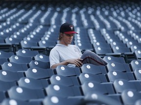 Arizona Diamondbacks starting pitcher Zack Greinke reads in the empty stands before a baseball game against the Colorado Rockies Monday, Sept. 10, 2018, in Denver.