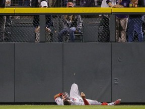 Philadelphia Phillies left fielder Aaron Altherr lays in the field after injuring himself on the wall during the fourth inning of a baseball game against the Colorado Rockies on Monday, Sept. 24, 2018, in Denver.