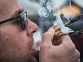 Brandon Bartelds smokes three joints at once while attending the 4-20 annual marijuana celebration, in Vancouver, B.C., on Friday April 20, 2018. The Manitoba government has set out fines of up to $2,500 for people who break the rules surrounding cannabis consumption. Once recreational use of the drug is legalized, people who smoke pot in a provincial park or campsite will face a fine of $672, including fees and surcharges.THE CANADIAN PRESS/Darryl Dyck
