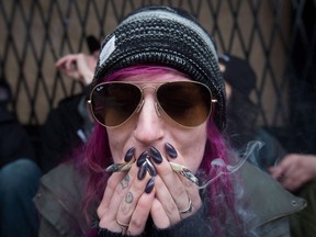 A woman smokes two joints during a sit-in as police officers raid the Cannabis Culture shop, in Vancouver, B.C., on Thursday March 9, 2017. Getting paid to smoke pot is no longer a toker's daydream. Toronto-based company AHLOT is offering $50 an hour to five so-called cannabis connoisseurs to sample various strains of marijuana.