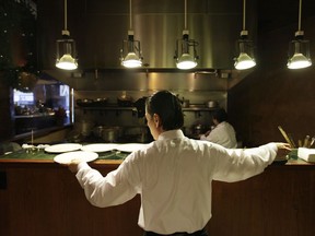 The minimum wage across the Prairies is going up, with raises in Alberta, Saskatchewan and Manitoba set to take effect Monday. A waiter reaches for plates at a restaurant in San Francisco in a Dec.7, 2011 file photo.