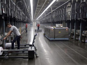 Workers exchange spools of thread as a robot picks up thread made from recycled plastic bottles at the Repreve Bottle Processing Center, part of the Unifi textile company in Yadkinville, N.C., on October 21, 2016.