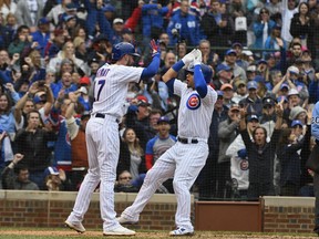 Chicago Cubs' Kris Bryant (17) and Willson Contreras, right, high five after they score on Contreras' home run during the fifth inning of a baseball game against the St. Louis Cardinals on Sunday, Sept. 30, 2018, in Chicago.