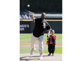 Kanye West, left, throws out a ceremonial first pitch as his son Saint watches before a baseball game between the Chicago Cubs and the Chicago White Sox, Sunday, Sept. 23, 2018, in Chicago.