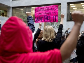 A protester of Supreme Court nominee Brett Kavanaugh wears a costume from the show "The Handmaid's Tale," and another protester holds up a sign that reads "Kavanaugh and GOP Want Women to Shut Up and Take It" on Capitol Hill in Washington, Monday, Sept. 24, 2018, as the Senate begins a week of scrutiny of President Donald Trump's nominee to the high court. Judge Brett Kavanaugh's nomination to the U.S. Supreme Court has been further imperiled by a second sexual-misconduct allegation, dating to his first year at Yale University.