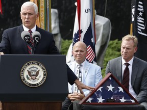 Vice President Mike Pence, left, gestures to an American flag that was used during the return of remains from the Korean War in Hawaii in August 2018, while presenting it to the Korean War Veterans Memorial Foundation, Thursday, Sept. 20, 2018, during a ceremony at the Korean War Veterans Memorial in Washington. At center is Richard Dean, Vice Chairman of the Korean War Veterans Memorial Foundation, and right is Deputy Secretary of Defense Patrick Shanahan.