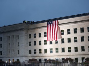 A U.S. flag is unfurled at sunrise on Tuesday, Sept. 11, 2018, at the Pentagon on the 17th anniversary of the Sept. 11, 2001, terrorist attacks.