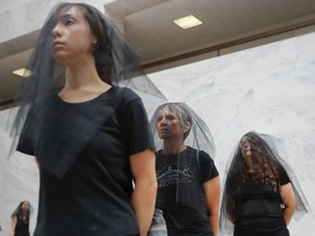Protesters in black veils walk the hallways of the Hart Senate Office building on the fourth day of the Senate Judiciary Committee confirmation hearing for President Donald Trump's Supreme Court nominee, Brett Kavanaugh, on Capitol Hill in Washington, Friday, Sept. 7, 2018.