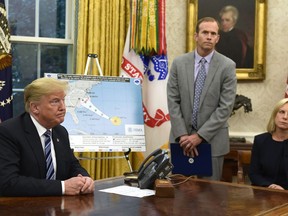 President Donald Trump, left, listens to a reporters question as FEMA Administrator Brock Long, center, and Homeland Security Secretary Kirstjen Nielsen, right, listen during a briefing on Hurricane Florence in the Oval Office of the White House in Washington, Tuesday, Sept. 11, 2018.