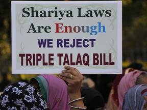 FILE - In this Jan. 7, 2018 file photo, an Indian Muslim woman holds a placard during a protest against a new draft law aimed at banning "Triple Talaq," a Muslim practice of instant divorce, in Ahmadabad, India. India's government on Wednesday, Sept. 19, approved an ordinance to implement a top court ruling striking down the Muslim practice that allows men to instantly divorce.
