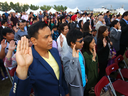 100 new Canadians say the oath during a citizenship ceremony in Calgary.