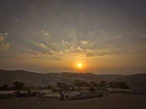 FILE - This Thursday, Sept. 13, 2018 file photo shows a sunrise over West Bank hamlet of Khan al-Ahmar. The Palestinian residents of Khan al-Ahmar cling to hopes that international pressure can save their strategically located West Bank hamlet from Israeli army bulldozers. After the West Bank hamlet lost its last legal protection against demolition late last week, Israeli forces could swoop in any day now to tear down the tiny desert community's few dozen shacks and schoolhouse made from recycled tires.