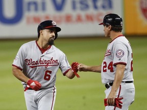 Washington Nationals' Anthony Rendon (6) is congratulated by first base coach Tim Bogar (24) after Rendon got a base hit during the first inning of a baseball game against the Miami Marlins, Tuesday, Sept. 18, 2018, in Miami.