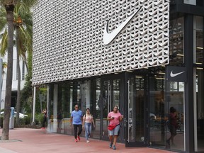 Shoppers walk past the Nike Miami store on the Lincoln Road Mall, Tuesday, Sept. 4, 2018, in Miami Beach, Fla. Nike's stock was falling in early trading on Tuesday following an announcement that former San Francisco 49ers quarterback Colin Kaepernick has a new deal with the athletic clothing and footwear maker.