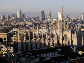 FILE - In this Jan. 4, 2017 file phtoo, the pinnacles of the Duomo gothic cathedral are lit by the afternoon sun and backdropped by the new Business Center, in Milan, northern Italy. Italy's three-pronged bid for the 2026 Winter Olympics has been reduced to a two-city candidacy featuring Milan and Cortina d'Ampezzo. Following Turin's exclusion, the Italian Olympic Committee is sending a delegation featuring Milan and Cortina representatives to meet with IOC leaders on Wednesday to update the situation. The move comes after government undersecretary and sports delegate Giancarlo Giorgetti told the Senate on Tuesday that the three-pronged proposal "is dead."