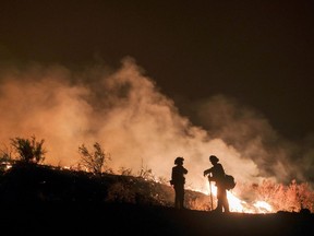 File - In this Aug. 9, 2018, file photo, firefighters keep watch the Holy Fire burning in the Cleveland National Forest in Lake Elsinore, Calif. Researchers have expanded a health-monitoring study of wildland firefighters after a previous study found season-long health declines and deteriorating reaction times.