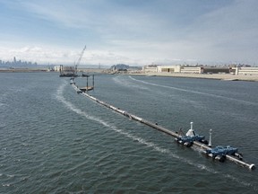 In this Monday, Aug. 27, 2018 photo provided by The Ocean Cleanup, a long floating boom that will be used to corral plastic litter in the Pacific Ocean is assembled in Alameda, Calif. Engineers will deploy a trash collection device to corral plastic litter floating between California and Hawaii in an attempt to clean up the world's largest garbage patch. The 2,000-foot (600-meter) long floating boom will be towed Saturday, Sept. 8, 2018, from San Francisco to the Great Pacific Garbage Patch, an island of trash twice the size of Texas. (The Ocean Cleanup via AP)