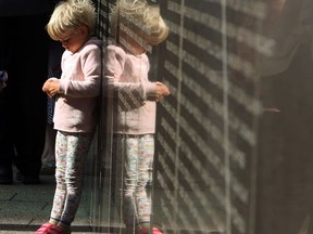 Three-year-old Savannah Hargrave, daughter of fallen firefighter James Hargrave of Cypress County Walsh Fire Station, Alberta, leans on the National Firefighter memorial wall as she and her family take part in Firefighters' National Memorial Day ceremony at the Canadian Firefighters Memorial in Ottawa on Sunday, September 9, 2018.
