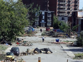 People walk past debris in a Gatineau, Que. neighbourhood on Saturday, September 22, 2018. A tornado on Friday afternoon tore roofs off of homes, overturned cars and felled power lines in the Ottawa community of Dunrobin and in Gatineau, Que.THE CANADIAN PRESS/Fred Chartrand