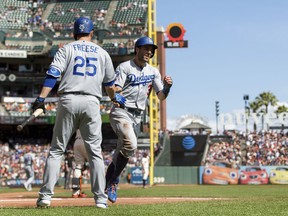 Los Angeles Dodgers Chris Taylor, right, celebrates with David Freese after scoring a run against the San Francisco Giants in the first inning of a baseball game in San Francisco, Sunday, Sept. 30, 2018.