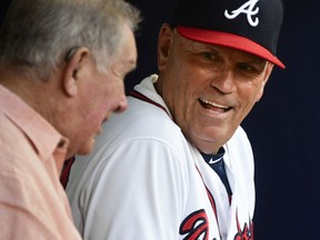 Atlanta Braves manager Brian Snitker talks to former manager Bobby Cox in the dugout before a baseball game against the St. Louis Cardinals, Monday, Sept. 17, 2018, in Atlanta.