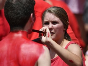 A young woman paints the body of a Georgia fan before the first half of an NCAA college football game between Georgia and Austin Peay, Saturday, Sept. 1, 2018, in Athens, Ga.