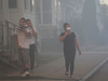 People cover their faces to protect themselves from heavy smoke from a fire on Bowdoin Street in Lawrence, Mass., Thursday, Sept. 13, 2018.