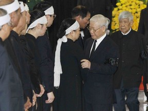 Communist Party General Secretary Nguyen Phu Trong, center, talks to Nguyen Thi Hien, widow of late Vietnamese President Tran Dai Quang in Hanoi, Vietnam, Wednesday, Sept. 26, 2018. Hundreds of mourners are paying tribute to the president who died of viral illness last week.