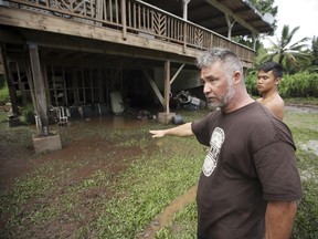 In this Wednesday, Sept. 12, 2018 photo, Honokohau Valley resident Mundy Gillcoat describes to his son how high flood waters raged outside their home in Maui, Hawaii. Honolulu officials are asking residents near a dam to stay alert for the possibility of evacuating as water levels in the reservoir rise amid heavy rains. Tropical Storm Olivia dumped heavy rains on Maui and Oahu as it crossed the state.