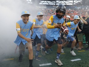 Members of the Honolulu Little League-champion baseball team run onto the field before an NCAA college football game between Rice and Hawaii on Saturday, Sept. 8, 2018, in Honolulu.