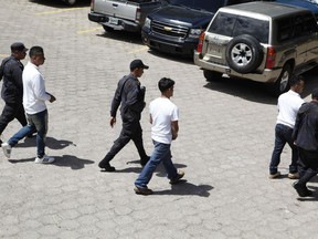 Men accused in the killing prize-winning Honduran indigenous and environmental rights activist Berta Caceres are escorted for trail in Tegucigalpa, Honduras, Monday, Sept. 17, 2018. Honduras' supreme court has indefinitely suspended the start of the trial of eight men accused in the 2016 killing of Caceres, citing five related filings pending at the criminal appeals court that have to be resolved.