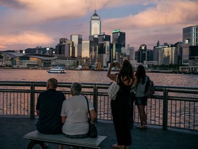 People take photographs with their mobile handsets on the Tsim Sha Tsui promenade as the Hong Kong skyline stands across Victoria Harbor in Hong Kong, in Hong Kong, China, on Monday, June 27, 2016.