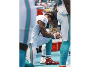 Miami Dolphins wide receiver Kenny Stills and wide receiver Albert Wilson, obscured, take a knee during the singing of the national anthem before an NFL football game against the Oakland Raiders, Sunday, Sept. 23, 2018, in Miami Gardens, Fla.