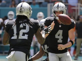 Oakland Raiders quarterback Derek Carr (4) pitches the ball to wide receiver Martavis Bryant (12) during the first half of an NFL football game against the Miami Dolphins, Sunday, Sept. 23, 2018 in Miami Gardens, Fla.